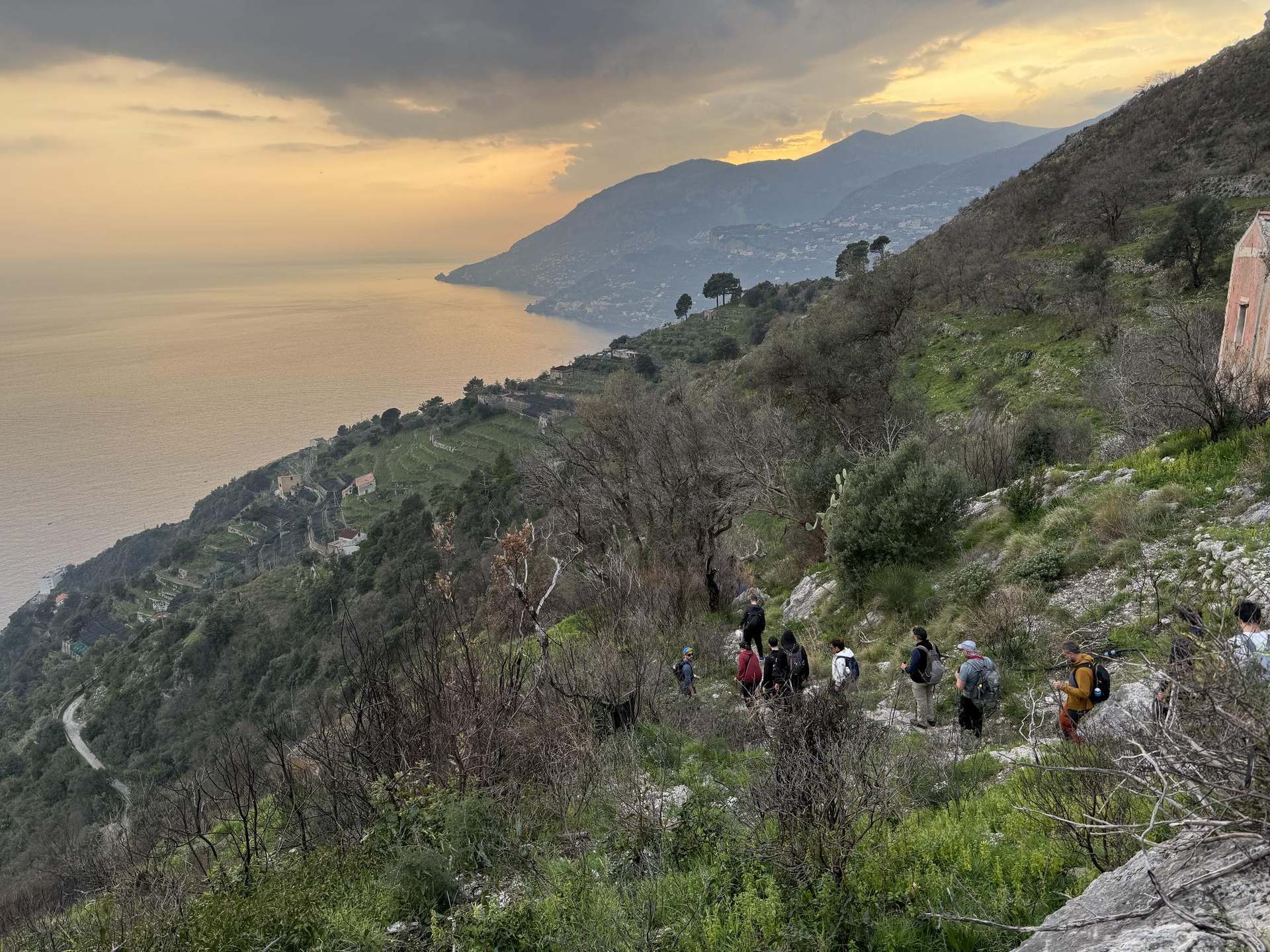 Hikers descending a ridge above the Amalfi Coast at sunset